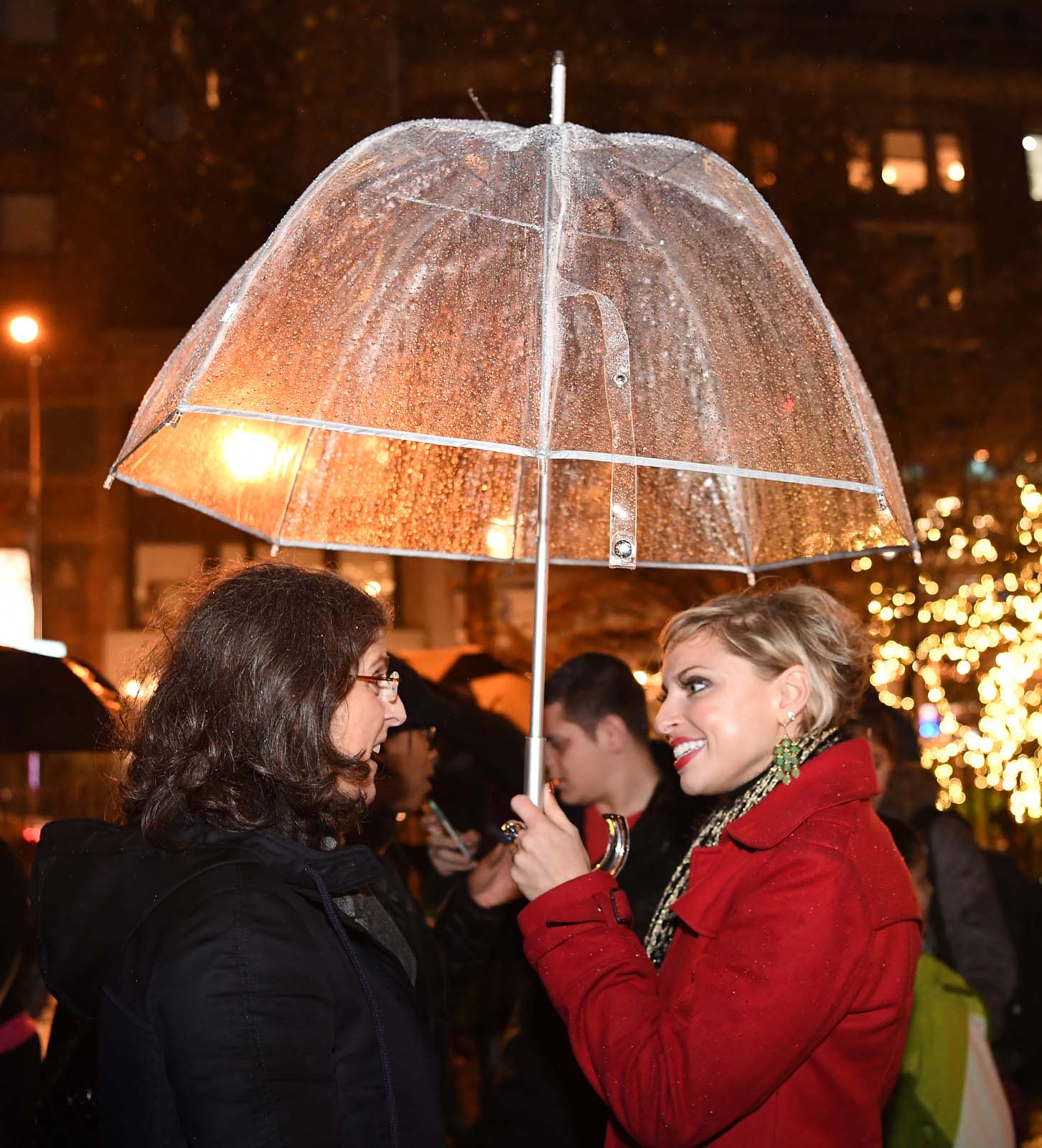 two women sharing umbrella and speaking